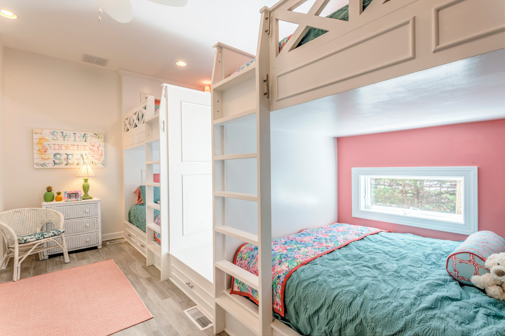 This is an example of a large beach style kids' bedroom for kids 4-10 years old and girls in Other with pink walls, light hardwood floors and grey floor.
