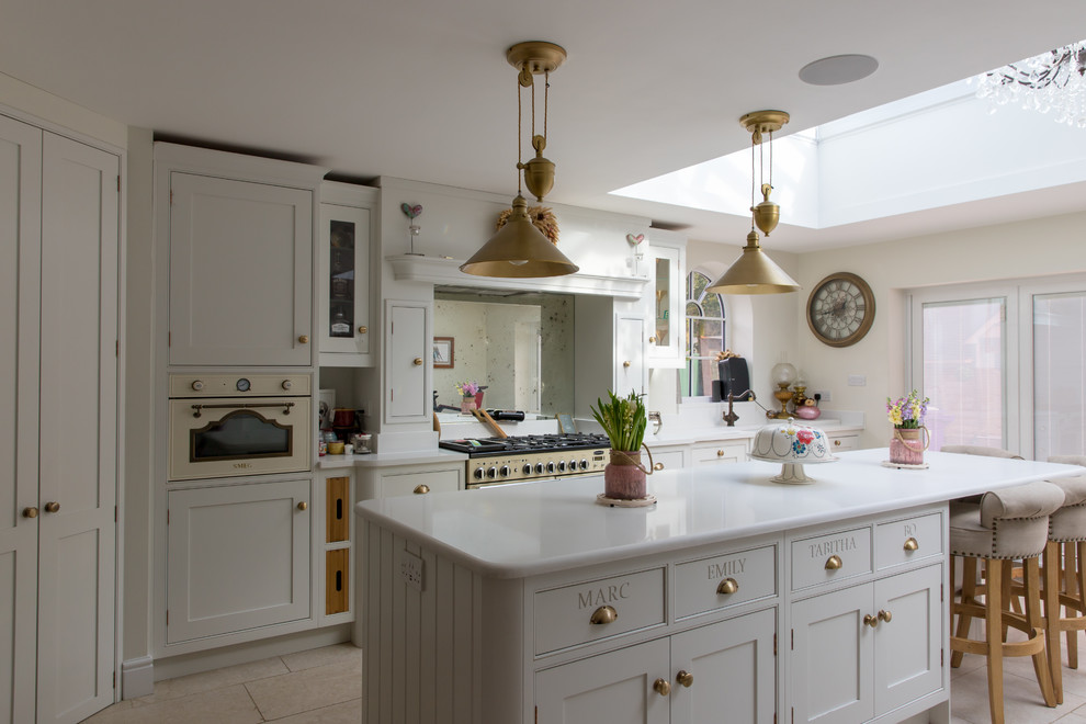 Inspiration for a large traditional l-shaped eat-in kitchen in Hertfordshire with a single-bowl sink, shaker cabinets, yellow cabinets, soapstone benchtops, metallic splashback, mirror splashback, stainless steel appliances, porcelain floors, with island, beige floor and white benchtop.