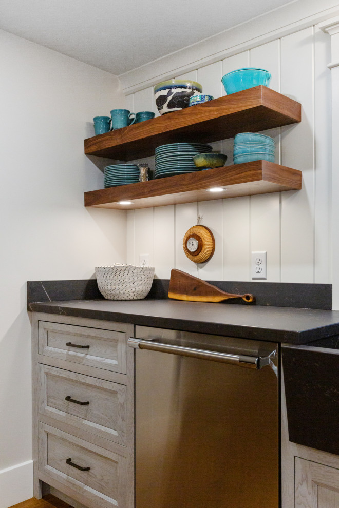 ボストンにある高級な中くらいなエクレクティックスタイルのおしゃれなキッチン (エプロンフロントシンク、フラットパネル扉のキャビネット、グレーのキャビネット、クオーツストーンカウンター、白いキッチンパネル、木材のキッチンパネル、シルバーの調理設備、無垢フローリング、茶色い床、黒いキッチンカウンター) の写真