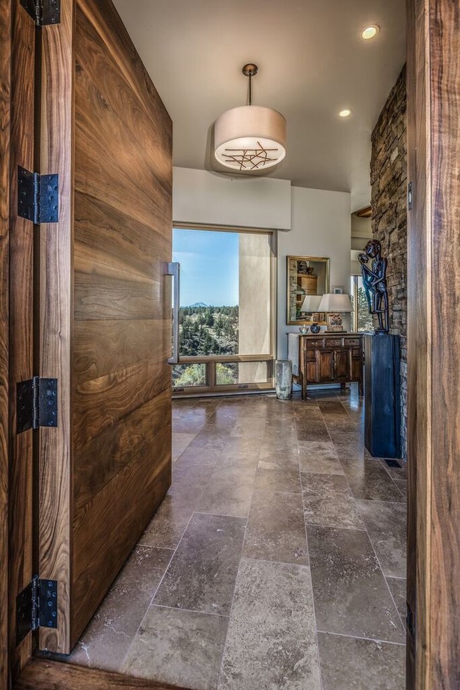Example of a mid-sized mountain style travertine floor foyer design with beige walls and a dark wood front door