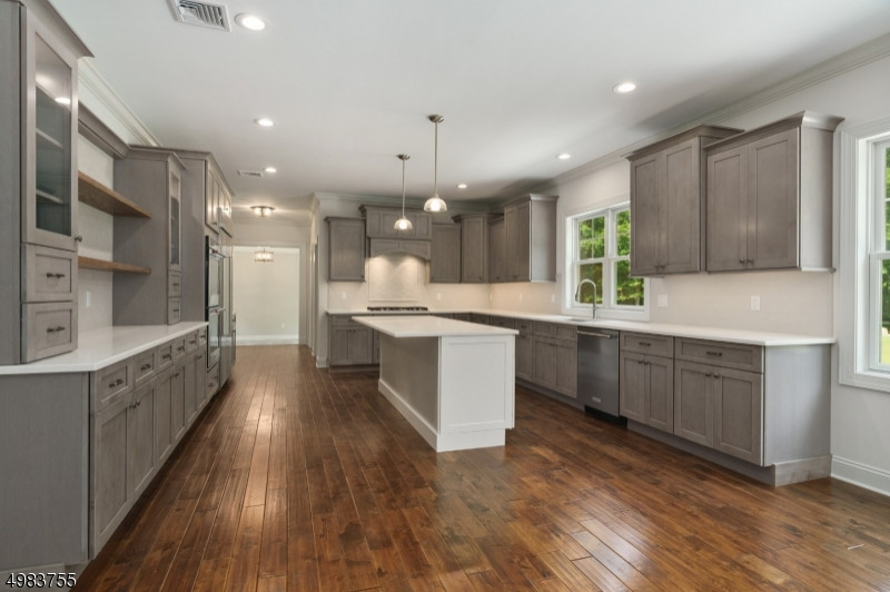 Photo of a large traditional u-shaped kitchen/diner in New York with a submerged sink, shaker cabinets, grey cabinets, engineered stone countertops, white splashback, metro tiled splashback, stainless steel appliances, medium hardwood flooring, an island, brown floors and white worktops.