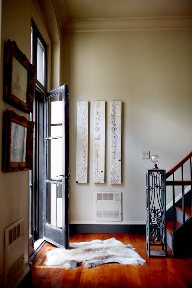Inspiration for a mid-sized eclectic front door in Boston with beige walls, medium hardwood floors, a black front door and orange floor.