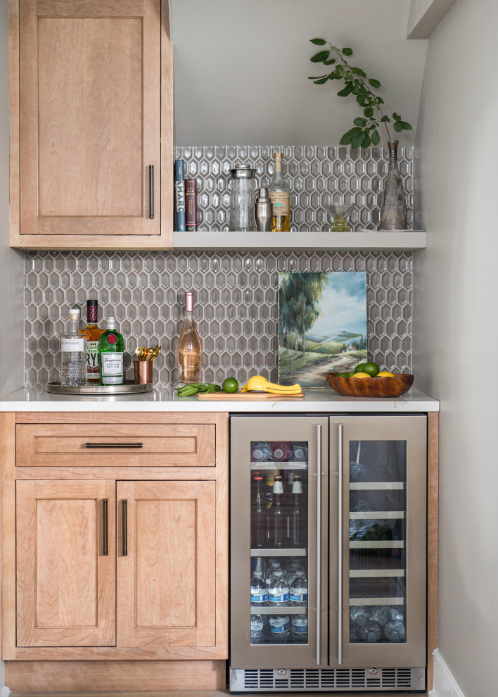 Photo of a small transitional single-wall home bar in Chicago with shaker cabinets, medium wood cabinets, quartz benchtops, brown splashback, mosaic tile splashback and white benchtop.