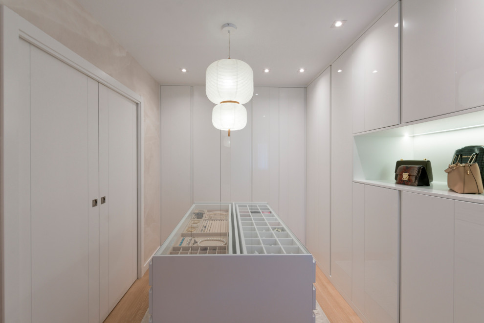 Large contemporary women's dressing room in Other with flat-panel cabinets, white cabinets, laminate floors and brown floor.