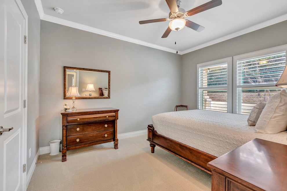This is an example of a mid-sized traditional guest bedroom in Austin with grey walls, carpet, no fireplace and beige floor.