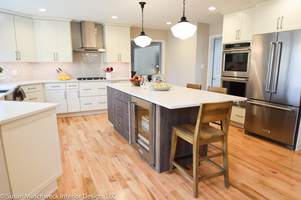 Inspiration for a large transitional light wood floor open concept kitchen remodel with shaker cabinets, white cabinets, quartz countertops, gray backsplash, ceramic backsplash, stainless steel appliances, an island and white countertops