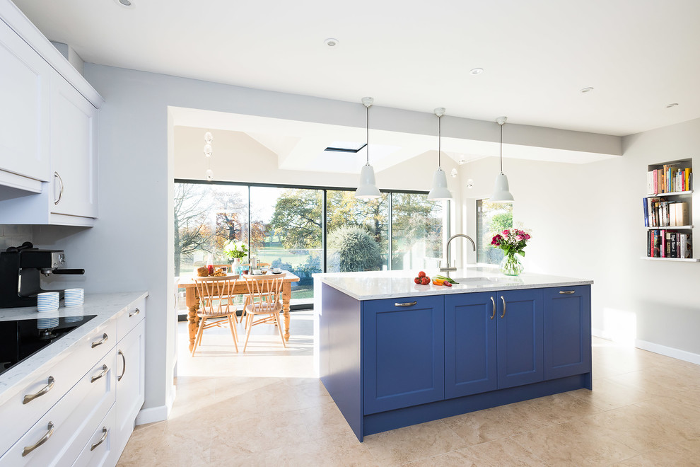 This is an example of a large transitional single-wall open plan kitchen in Buckinghamshire with a double-bowl sink, shaker cabinets, blue cabinets, quartzite benchtops, white splashback, subway tile splashback, black appliances, porcelain floors, with island, beige floor and yellow benchtop.