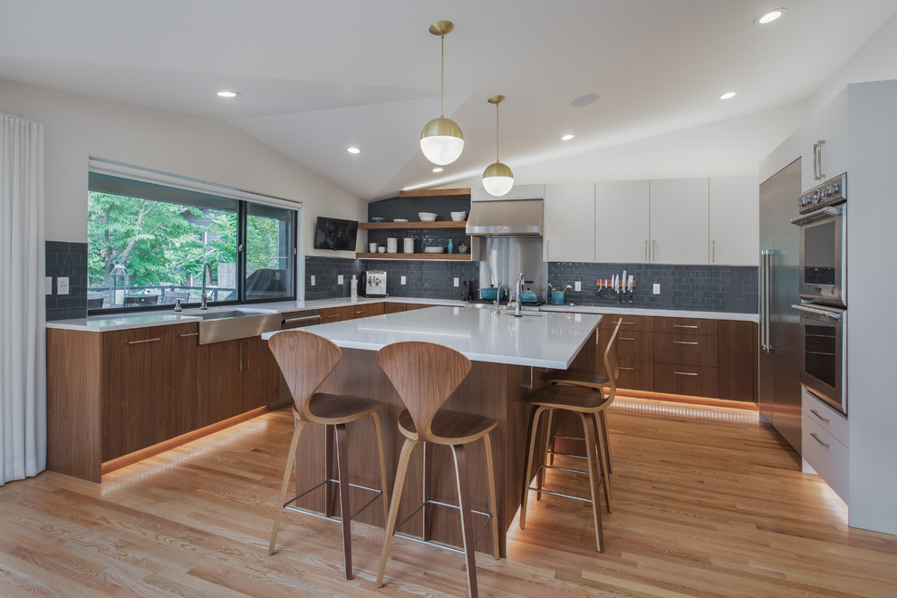 Design ideas for a large midcentury eat-in kitchen in Seattle with a farmhouse sink, flat-panel cabinets, white cabinets, quartz benchtops, blue splashback, ceramic splashback, stainless steel appliances, medium hardwood floors, with island, white benchtop and vaulted.