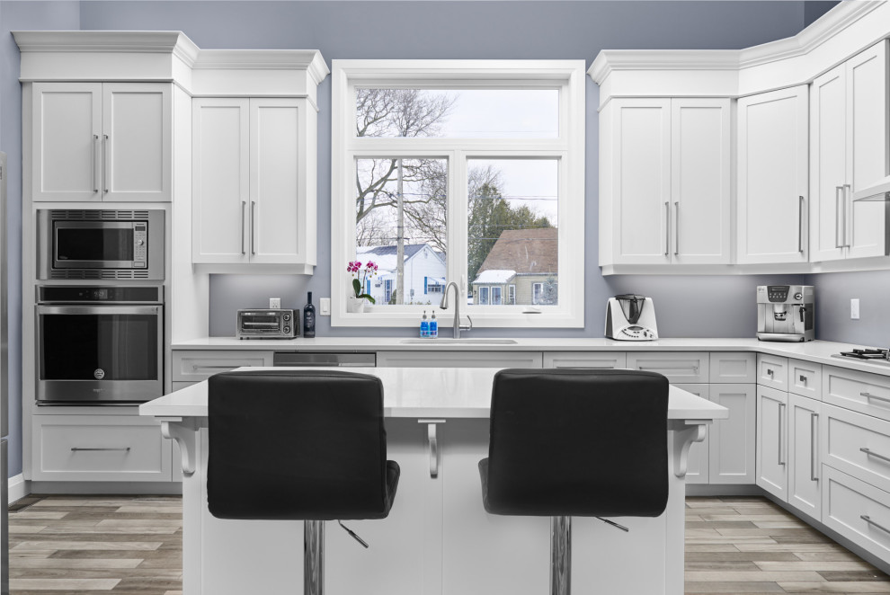 Enclosed kitchen - transitional l-shaped ceramic tile and gray floor enclosed kitchen idea in Toronto with an undermount sink, shaker cabinets, white cabinets, quartzite countertops, stainless steel appliances, an island and white countertops