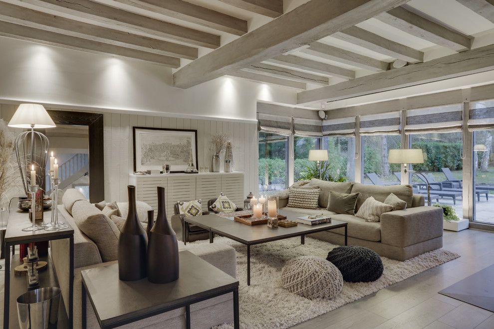 Inspiration for an expansive transitional open concept living room in Paris with a library, beige walls, laminate floors, a standard fireplace and grey floor.
