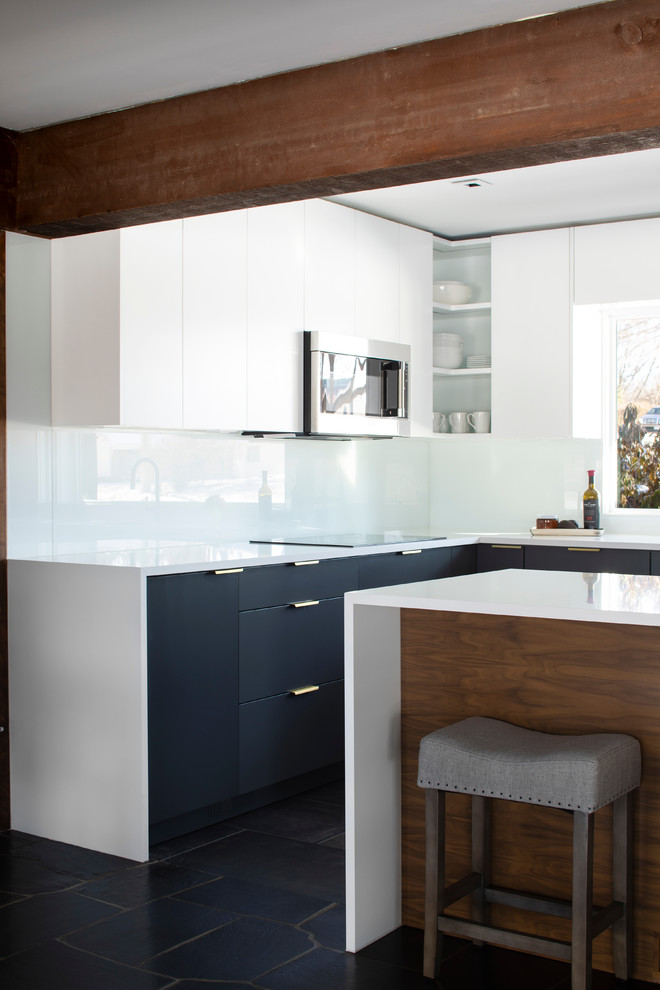 This is an example of a small midcentury l-shaped open plan kitchen in Omaha with an undermount sink, flat-panel cabinets, grey cabinets, quartzite benchtops, white splashback, glass sheet splashback, panelled appliances, porcelain floors, a peninsula, black floor and white benchtop.