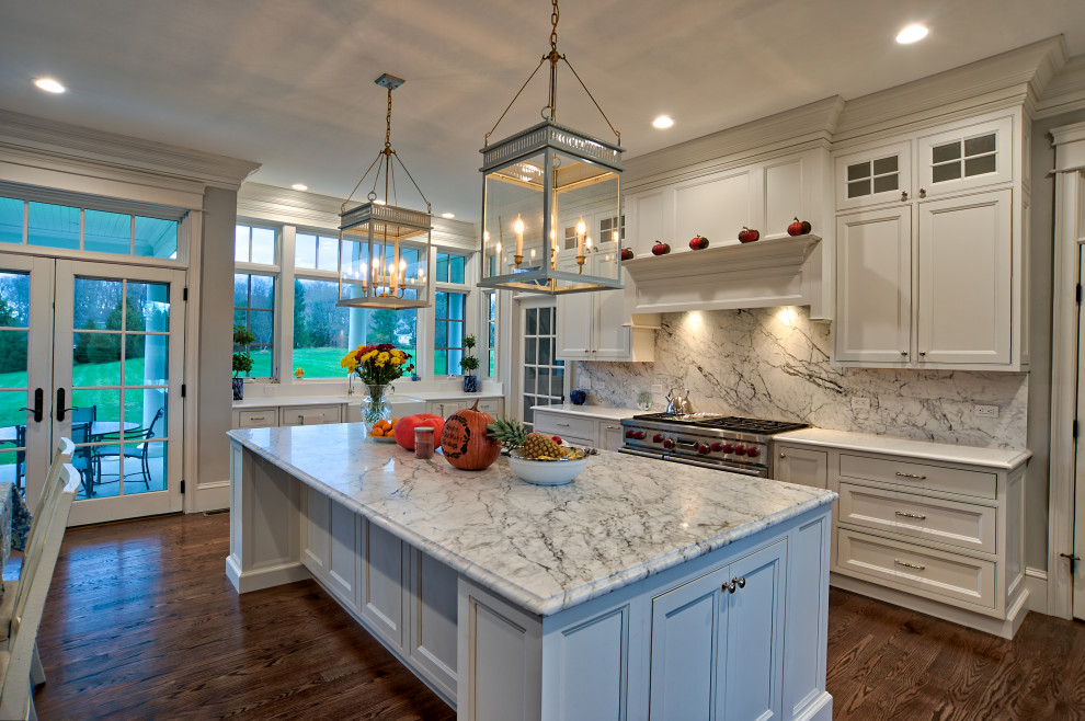 Photo of a large traditional u-shaped eat-in kitchen in Philadelphia with a farmhouse sink, beaded inset cabinets, white cabinets, quartz benchtops, white splashback, engineered quartz splashback, stainless steel appliances, medium hardwood floors, with island, brown floor and white benchtop.