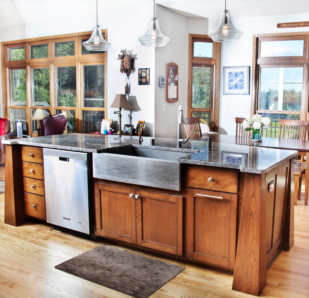 Inspiration for a transitional l-shaped light wood floor open concept kitchen remodel in Milwaukee with a farmhouse sink, shaker cabinets, medium tone wood cabinets, granite countertops, gray backsplash, glass tile backsplash, stainless steel appliances and an island