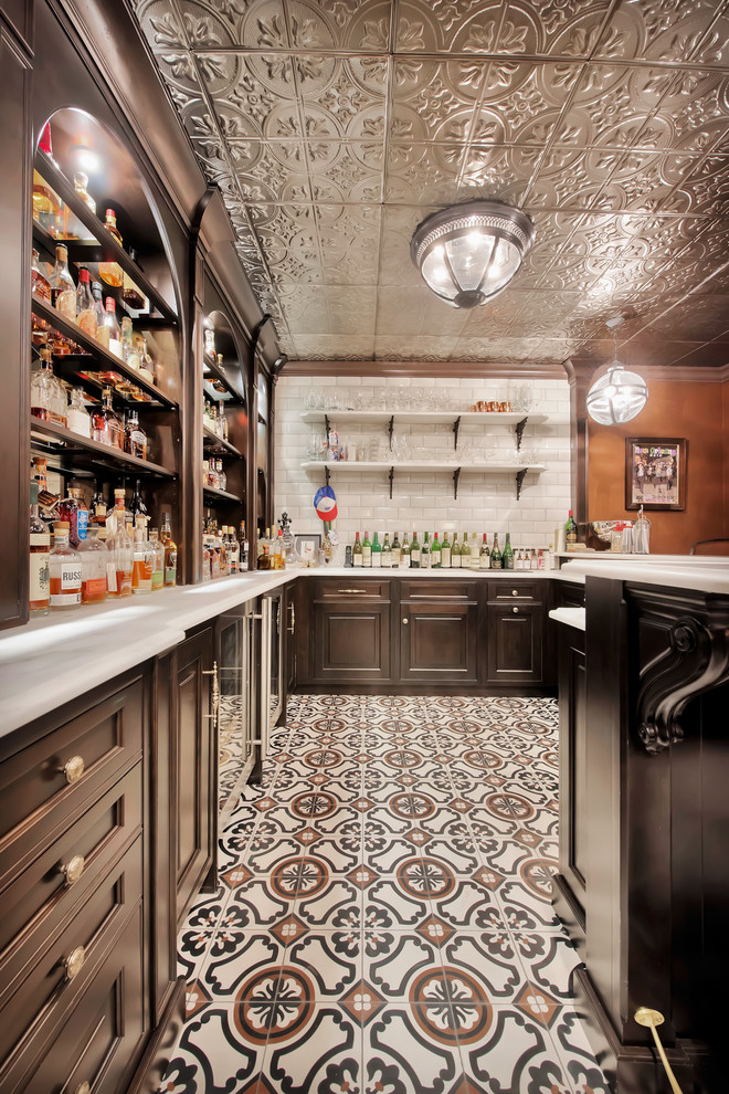 Traditional u-shaped seated home bar in Chicago with a drop-in sink, open cabinets, dark wood cabinets, white splashback, ceramic splashback, ceramic floors and multi-coloured floor.