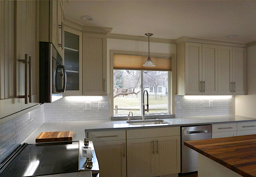 Example of a mid-sized transitional l-shaped kitchen design in Boise with an undermount sink, shaker cabinets, white cabinets, quartz countertops, white backsplash, ceramic backsplash, stainless steel appliances, an island and gray countertops