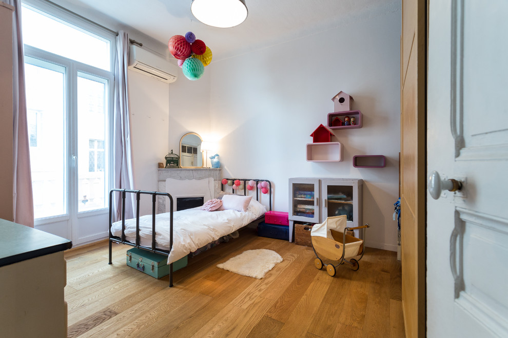 Large transitional kids' bedroom in Nice with white walls and medium hardwood floors for kids 4-10 years old and girls.