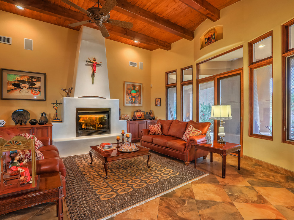This is an example of a mid-sized open concept living room in Albuquerque with multi-coloured walls, slate floors, a standard fireplace, a plaster fireplace surround, no tv and multi-coloured floor.