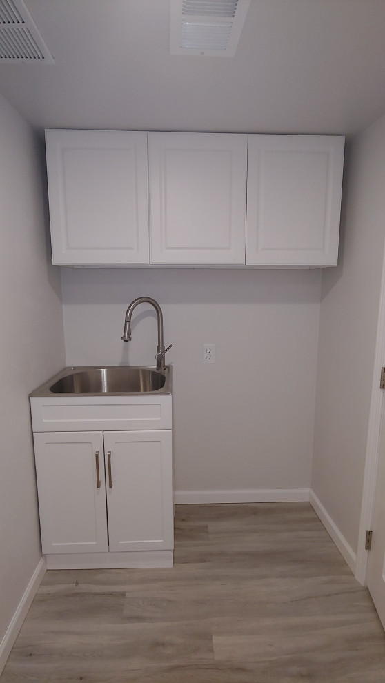Small transitional dedicated laundry room in Other with an utility sink, flat-panel cabinets, white cabinets, stainless steel benchtops, vinyl floors and grey floor.