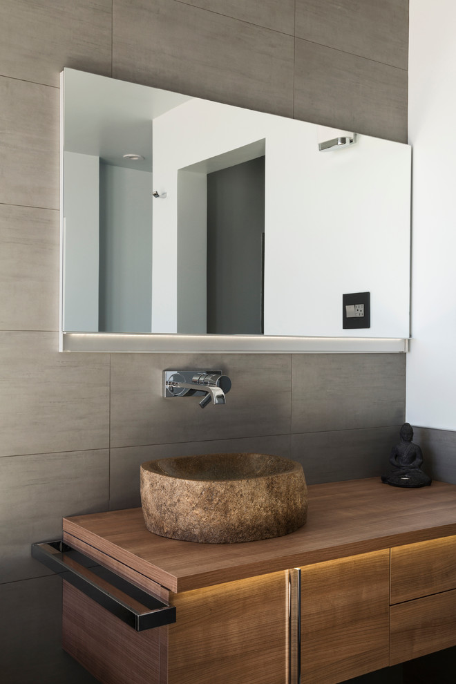 This is an example of a contemporary powder room in New York with flat-panel cabinets, light wood cabinets, a vessel sink, wood benchtops and brown benchtops.