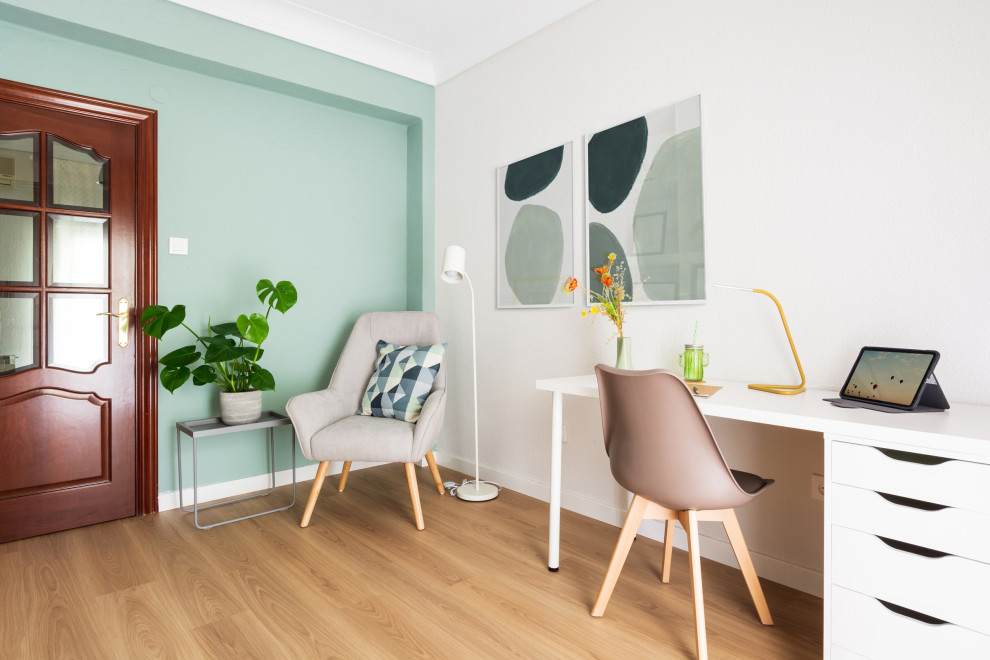 Cette image montre un bureau nordique de taille moyenne et de type studio avec un mur vert, un sol en bois brun, un bureau indépendant et un sol marron.