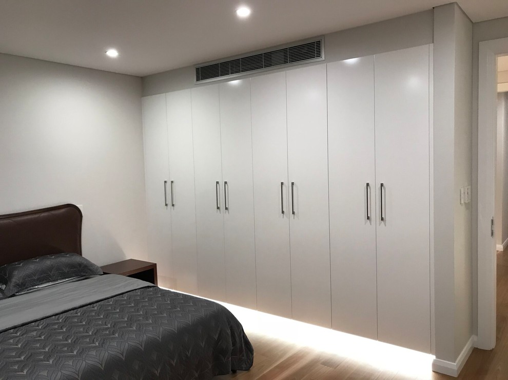 Large modern gender-neutral built-in wardrobe in Sydney with flat-panel cabinets and white cabinets.