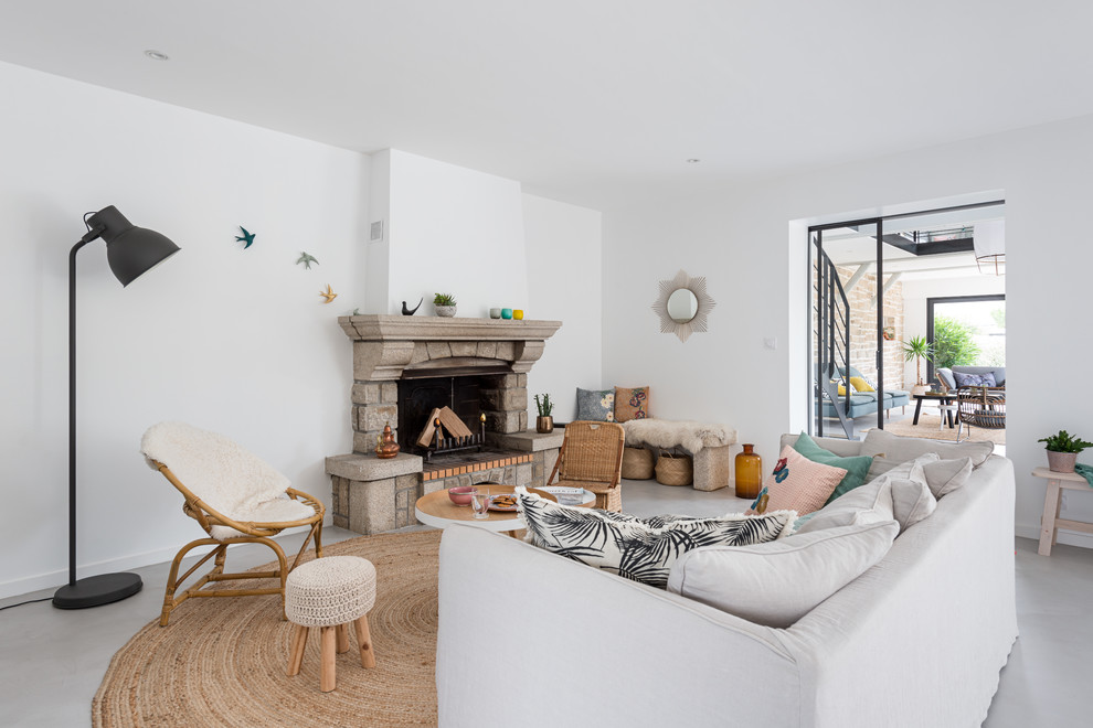 This is an example of a large beach style open concept living room with a library, white walls, concrete floors, a standard fireplace, a stone fireplace surround, grey floor and no tv.