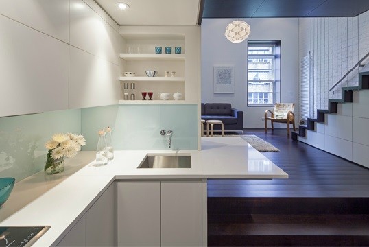 Small modern l-shaped kitchen in New York with white cabinets, glass sheet splashback, stainless steel appliances, dark hardwood floors, an undermount sink, flat-panel cabinets, white splashback and a peninsula.