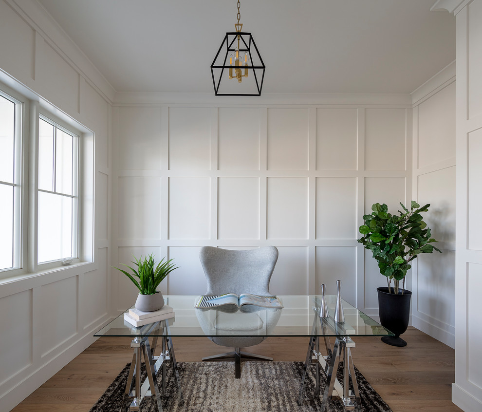 Ejemplo de despacho campestre pequeño con paredes blancas, suelo de madera en tonos medios, escritorio independiente, suelo gris y panelado