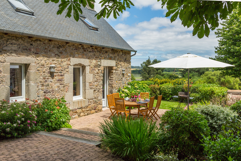 Country backyard patio in Rennes with brick pavers and no cover.