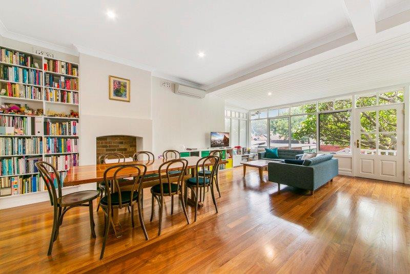 This is an example of a large contemporary open plan dining in Sydney with white walls, medium hardwood floors, a standard fireplace, a brick fireplace surround and brown floor.