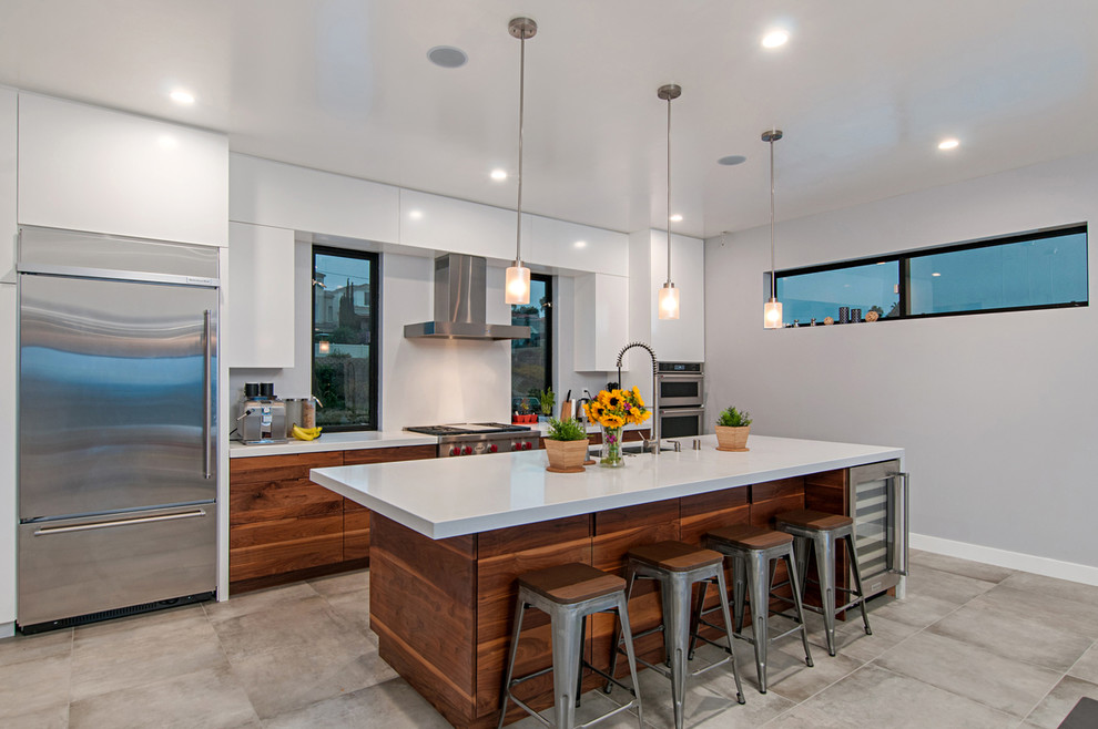 Photo of a mid-sized modern galley separate kitchen in San Diego with flat-panel cabinets, white cabinets, quartz benchtops, stainless steel appliances, cement tiles, with island and grey floor.