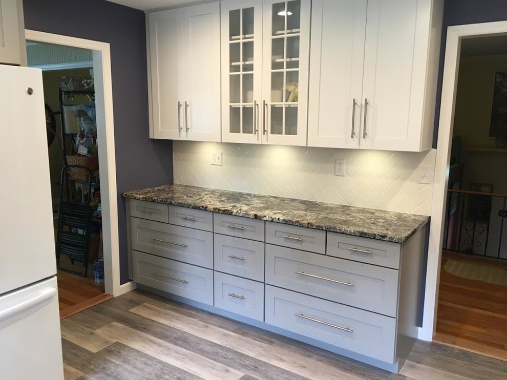 Eat-in kitchen - mid-sized transitional single-wall vinyl floor eat-in kitchen idea in New York with an undermount sink, shaker cabinets, white cabinets, granite countertops, white backsplash, subway tile backsplash, white appliances and an island