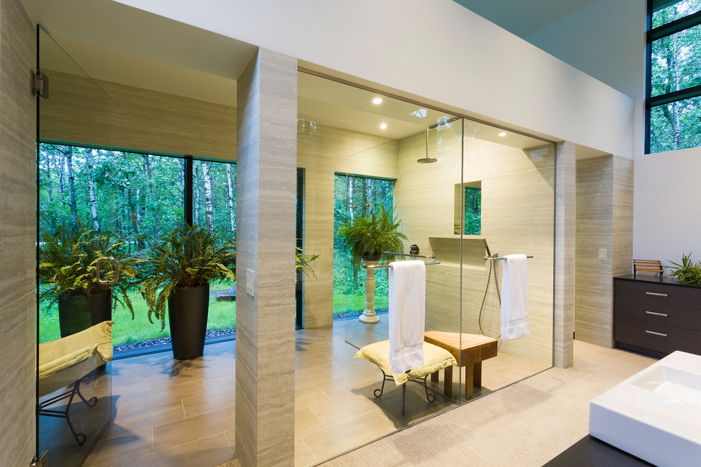 This is an example of an expansive contemporary master bathroom in Other with flat-panel cabinets, dark wood cabinets, a curbless shower, a one-piece toilet, beige tile, travertine, white walls, porcelain floors, a vessel sink, granite benchtops, beige floor, an open shower and black benchtops.
