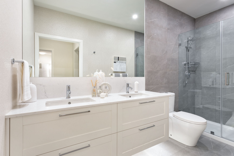 Photo of a mid-sized transitional master bathroom in Vancouver with shaker cabinets, beige cabinets, an alcove shower, a one-piece toilet, white tile, porcelain tile, beige walls, porcelain floors, an undermount sink, quartzite benchtops, grey floor, a hinged shower door, white benchtops, a double vanity and a floating vanity.