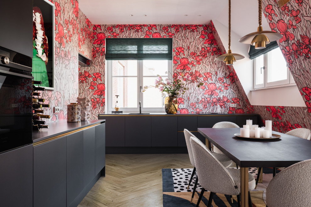 This is an example of a large contemporary l-shaped eat-in kitchen in Amsterdam with grey cabinets, medium hardwood floors, grey benchtop, flat-panel cabinets, multi-coloured splashback, black appliances and brown floor.