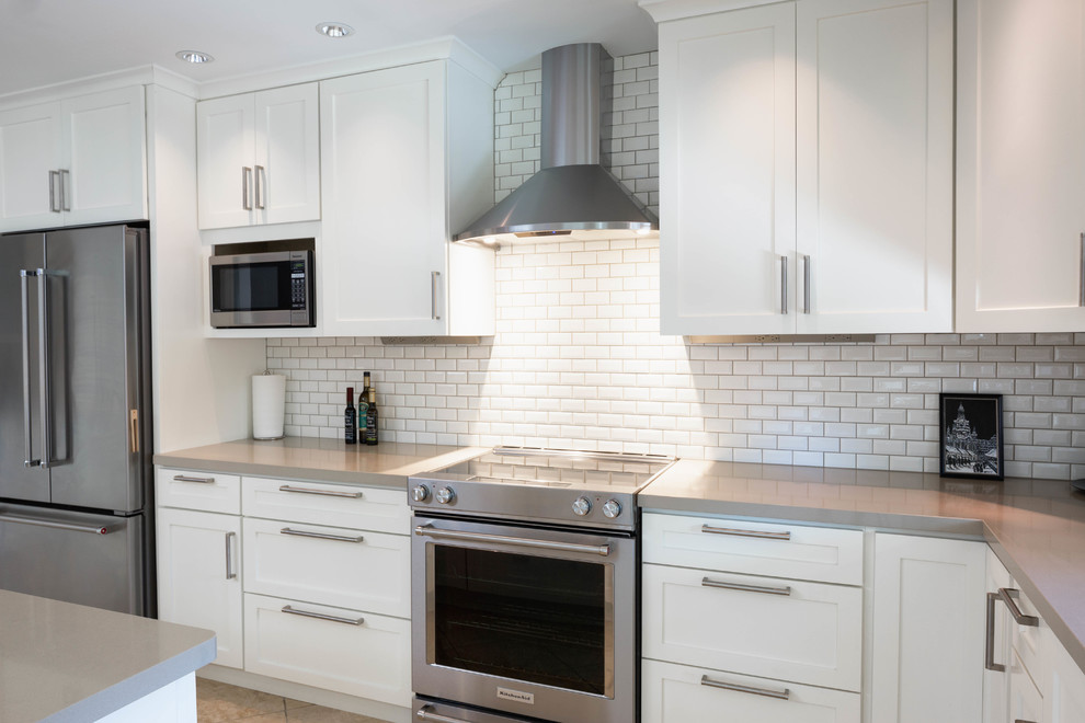 Inspiration for a large transitional travertine floor and beige floor eat-in kitchen remodel in Phoenix with an undermount sink, shaker cabinets, white cabinets, quartz countertops, beige backsplash, subway tile backsplash, stainless steel appliances and an island