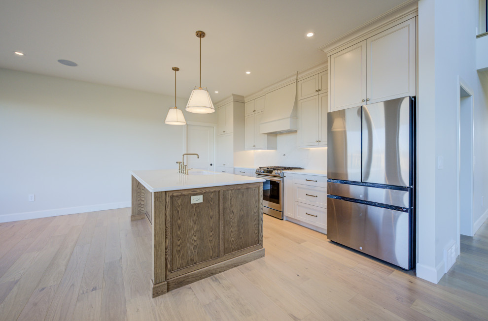 Inspiration for a mid-sized transitional single-wall light wood floor open concept kitchen remodel in Toronto with an undermount sink, shaker cabinets, quartz countertops, white backsplash, quartz backsplash, stainless steel appliances, an island, white countertops and medium tone wood cabinets