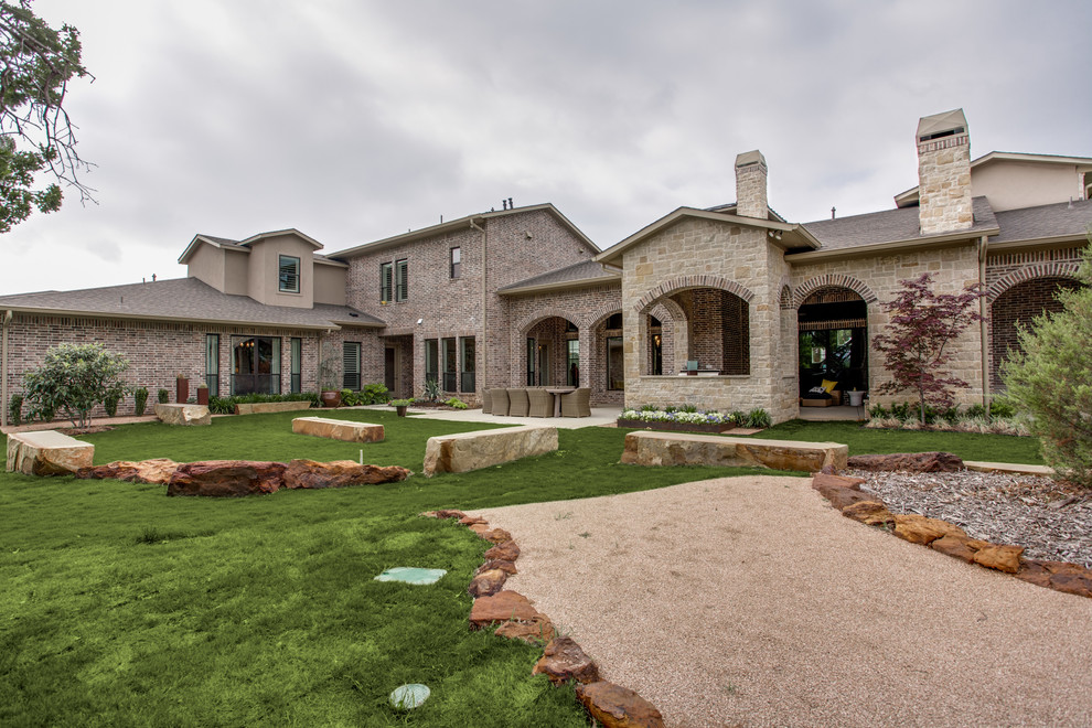 Inspiration for a mid-sized country two-storey beige exterior in Dallas with stone veneer and a clipped gable roof.