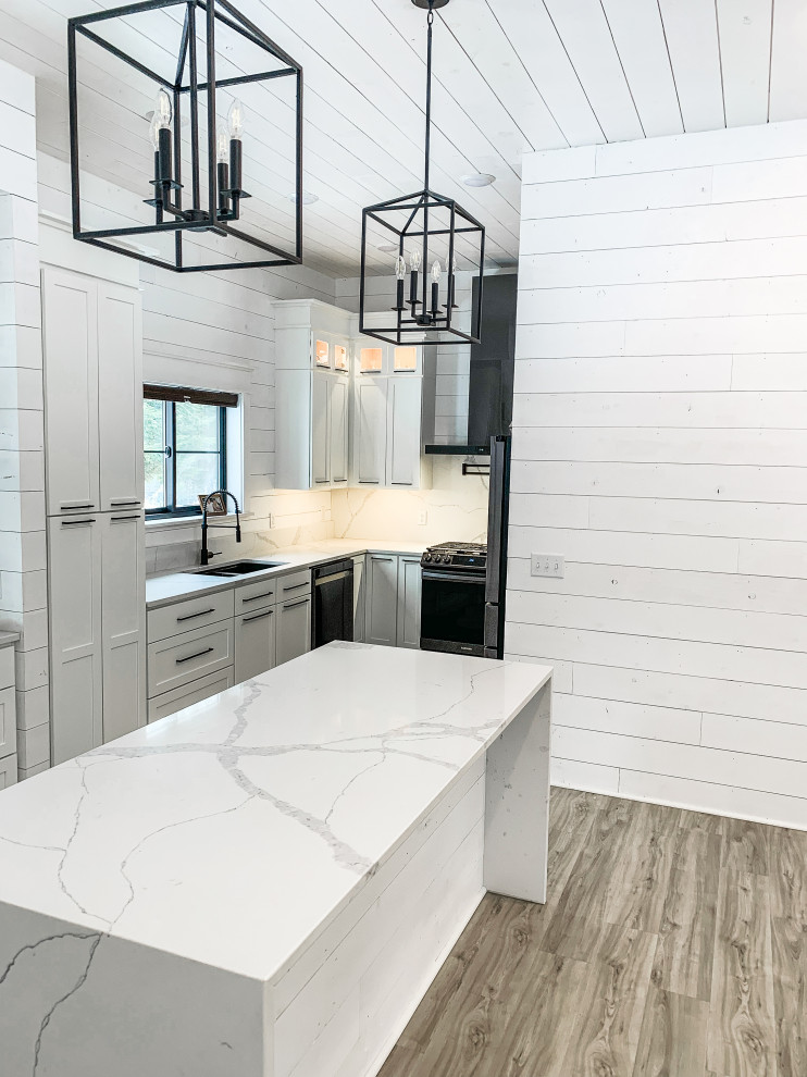 Inspiration for a large country u-shaped open plan kitchen in Minneapolis with an undermount sink, shaker cabinets, white cabinets, quartzite benchtops, white splashback, engineered quartz splashback, black appliances, laminate floors, with island, brown floor, white benchtop and timber.