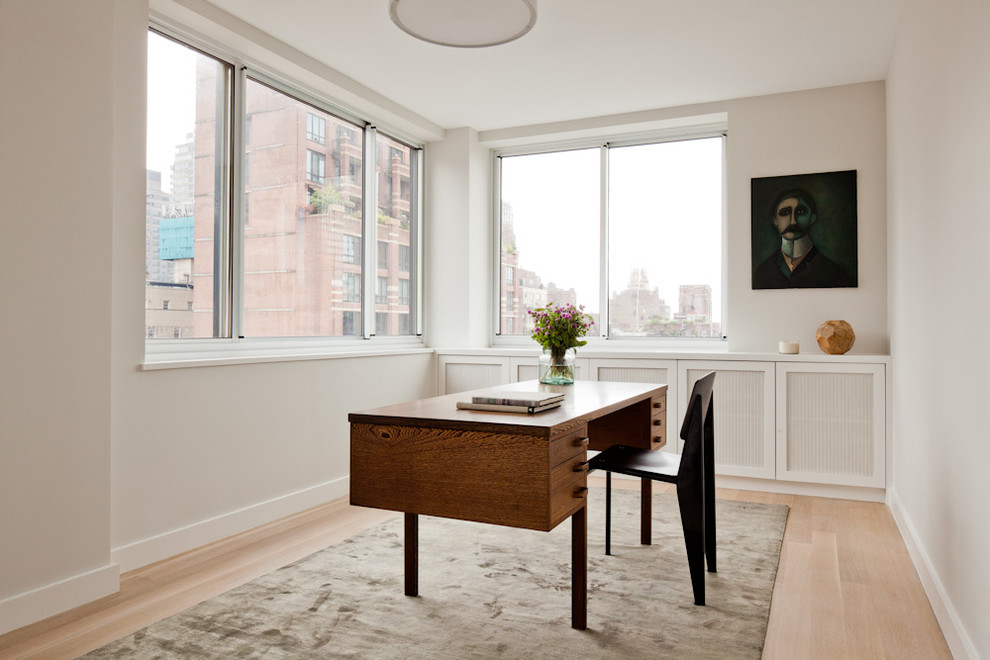 Mid-sized contemporary study room in New York with beige walls, light hardwood floors, no fireplace, a freestanding desk and beige floor.