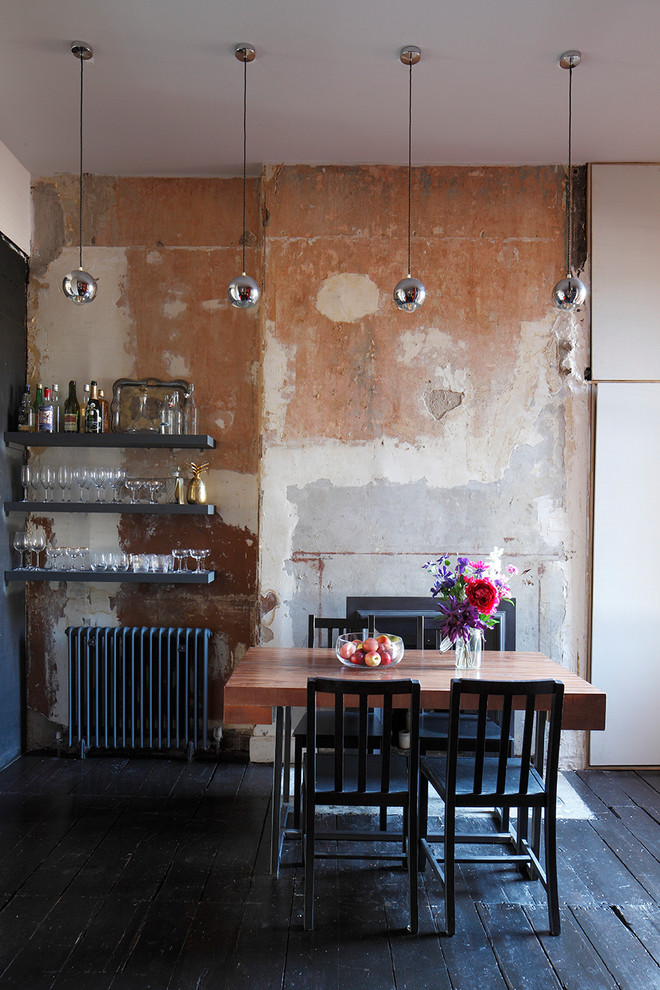 Inspiration for a mid-sized industrial dining room in London with beige walls, dark hardwood floors and a standard fireplace.