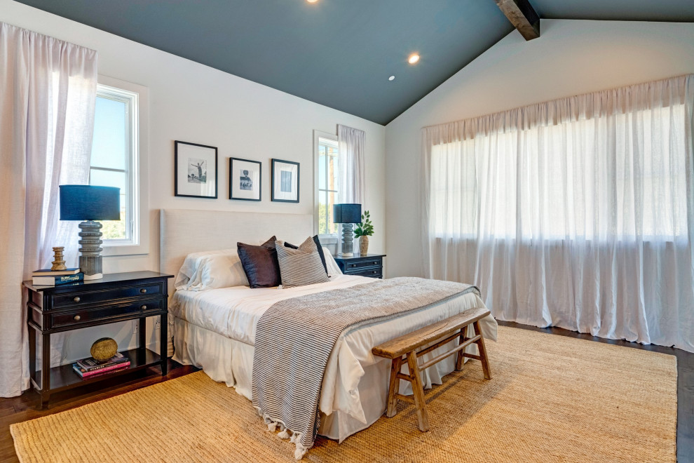 This is an example of a country master bedroom in Los Angeles with white walls, dark hardwood floors, brown floor and vaulted.