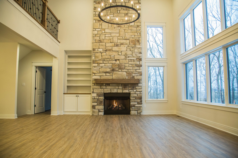 Inspiration for a large contemporary open concept living room in Indianapolis with medium hardwood floors, a standard fireplace, a stone fireplace surround, brown floor and vaulted.