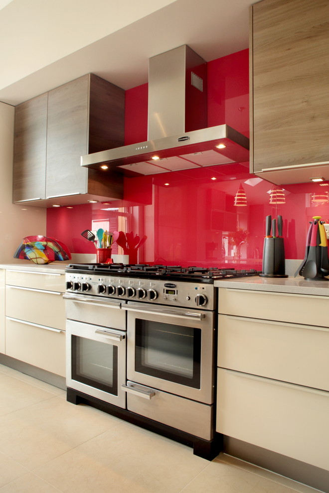 Photo of a contemporary kitchen in Buckinghamshire with flat-panel cabinets, beige cabinets, red splashback, glass sheet splashback and stainless steel appliances.