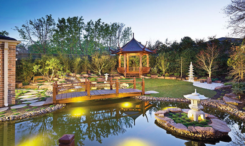 This is an example of a large asian backyard shaded garden in Toronto with a water feature.