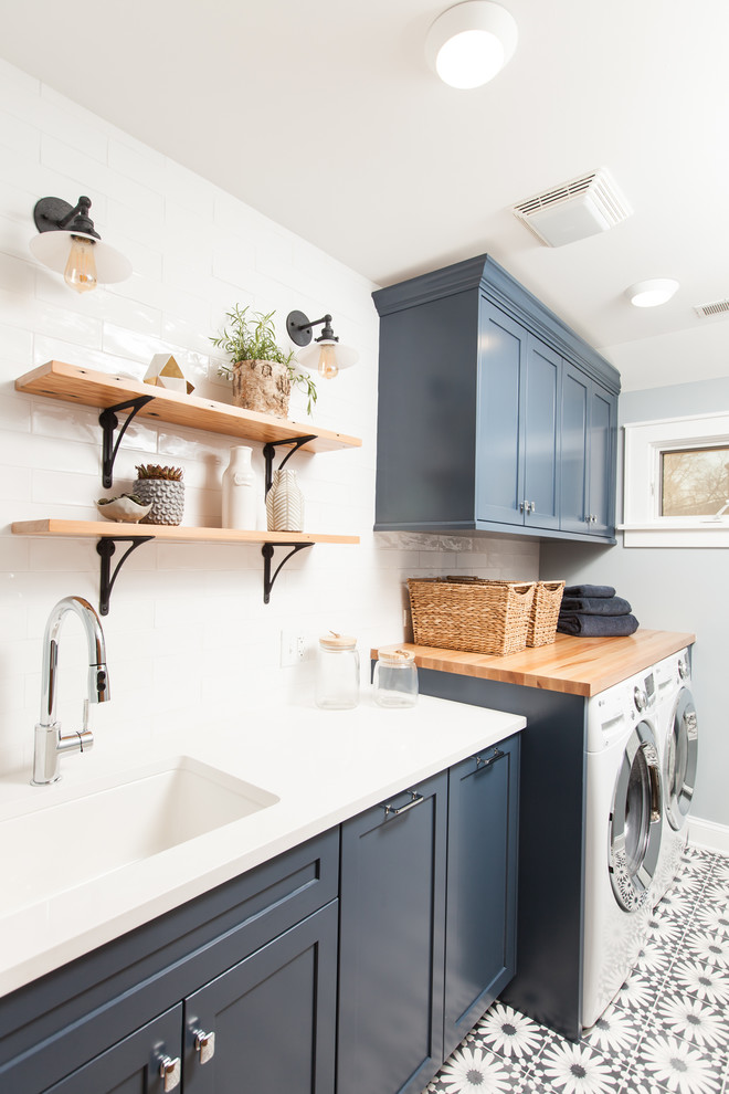 Design ideas for a mid-sized modern single-wall dedicated laundry room in Chicago with an undermount sink, shaker cabinets, blue cabinets, quartz benchtops, blue walls, concrete floors, a side-by-side washer and dryer, blue floor and white benchtop.