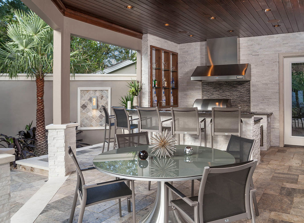 Inspiration for a large modern backyard patio in Tampa with an outdoor kitchen, natural stone pavers and a roof extension.