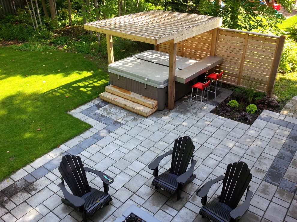 This is an example of a mid-sized modern backyard patio in Toronto with tile and a pergola.