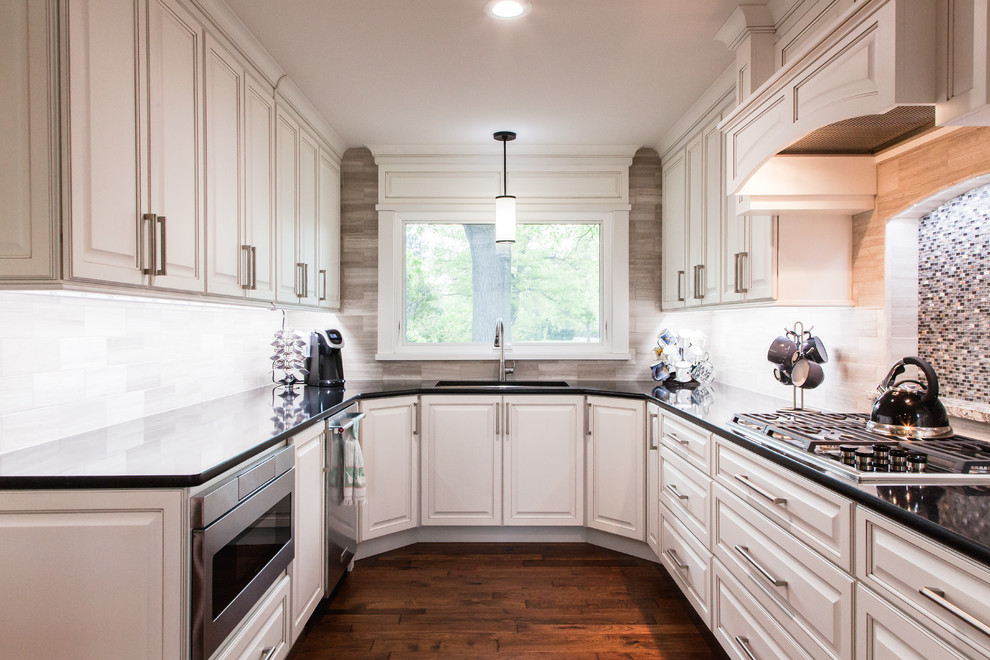 Design ideas for a large transitional galley kitchen pantry in Wichita with an undermount sink, raised-panel cabinets, white cabinets, quartzite benchtops, multi-coloured splashback, limestone splashback, stainless steel appliances, medium hardwood floors, with island and brown floor.