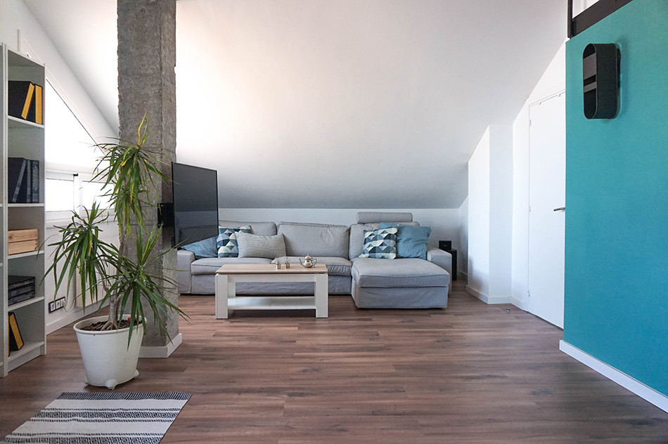 Modelo de sala de estar tipo loft urbana de tamaño medio sin chimenea con paredes blancas, suelo laminado, televisor en una esquina y suelo marrón